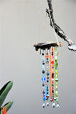Beaded Suncatcher with blue, red and green glass beads on jacaranda wood hanging on a tree branch