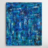 An abstract canvas painting featuring a textured, vertical brushstroke pattern in various shades of blue, teal, and white, displayed against a clean white wall.