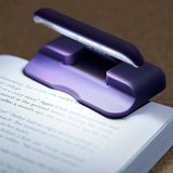 Purple Adjustable Clip-on LED Book Light clipped onto the edge of  a book 